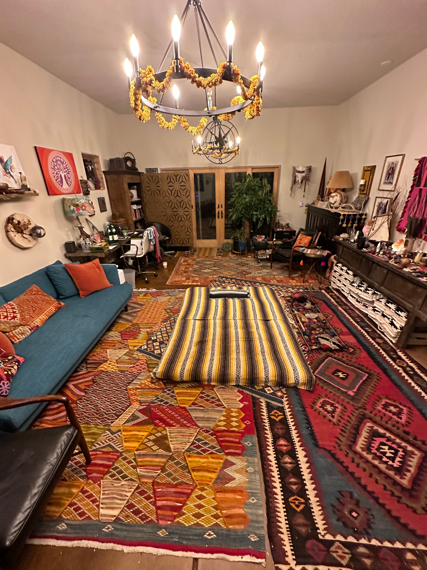 Sunlit healing studio with chandelier, altar shelves, and hand drums