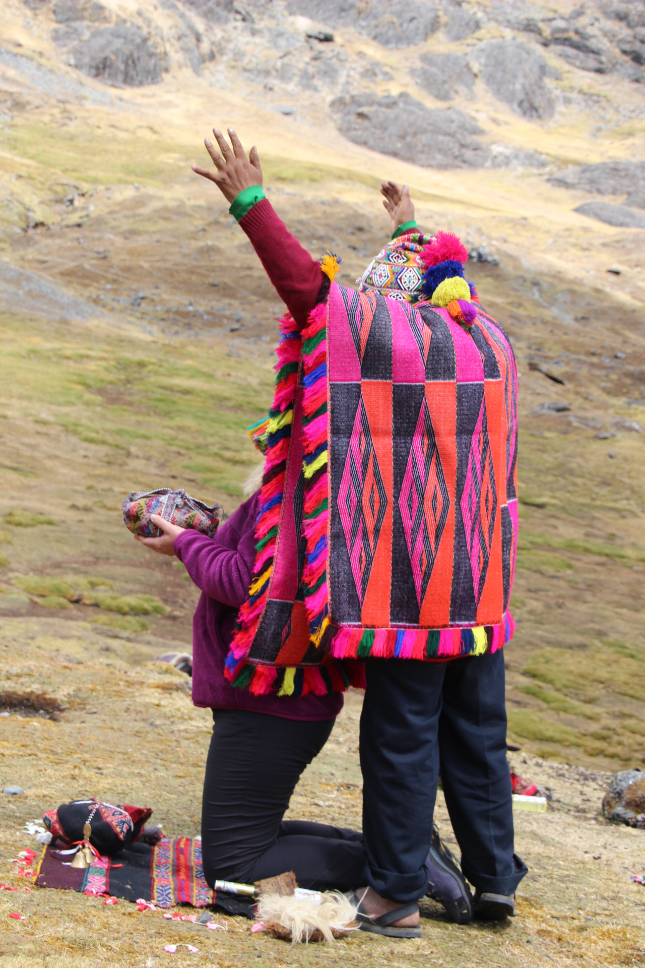 Q'ero shaman in prayer with arms raised on the high Andes mountainside