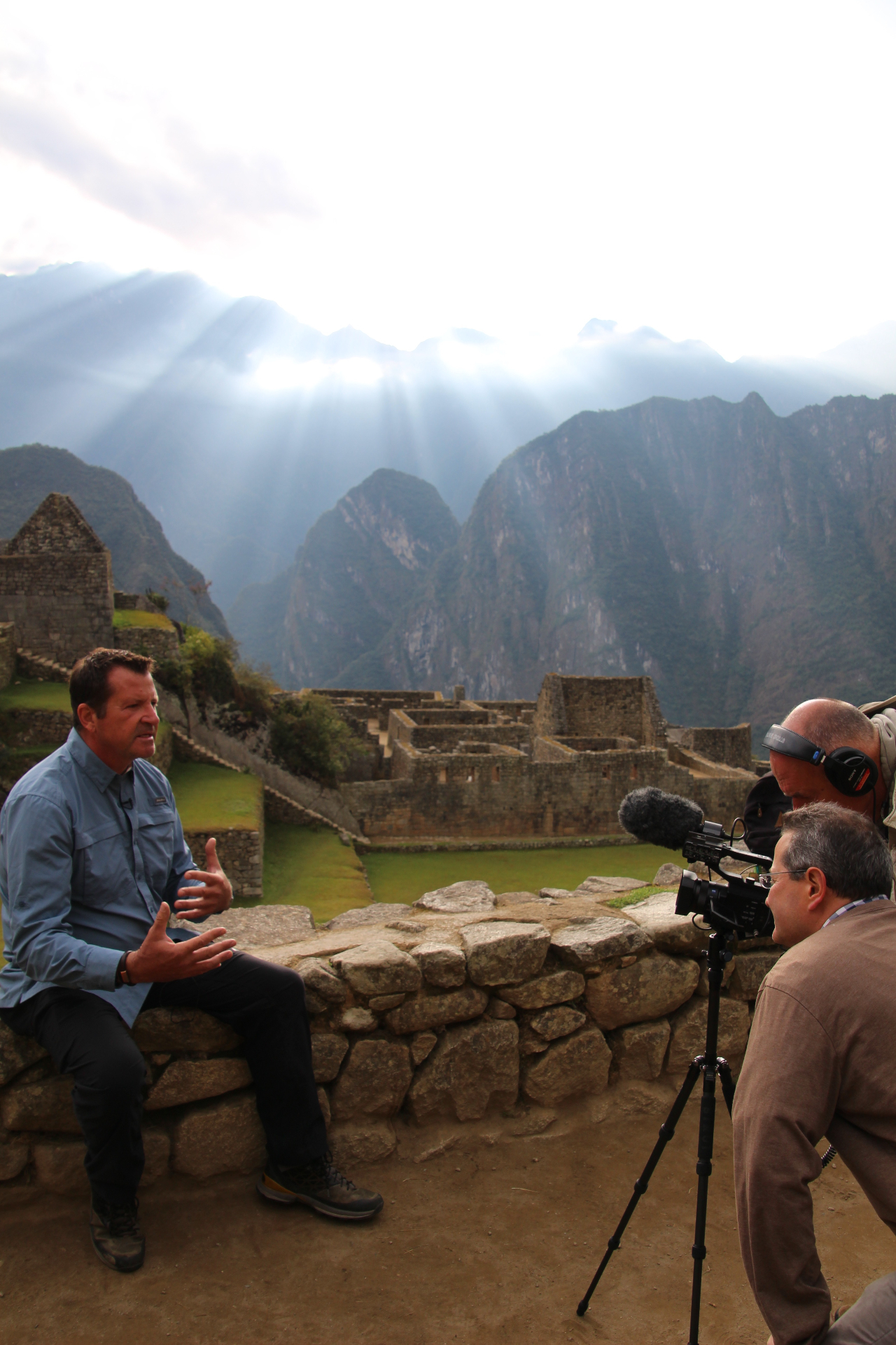 John Whitehorse being interviewed at Machu Picchu with sun rays over the Andes