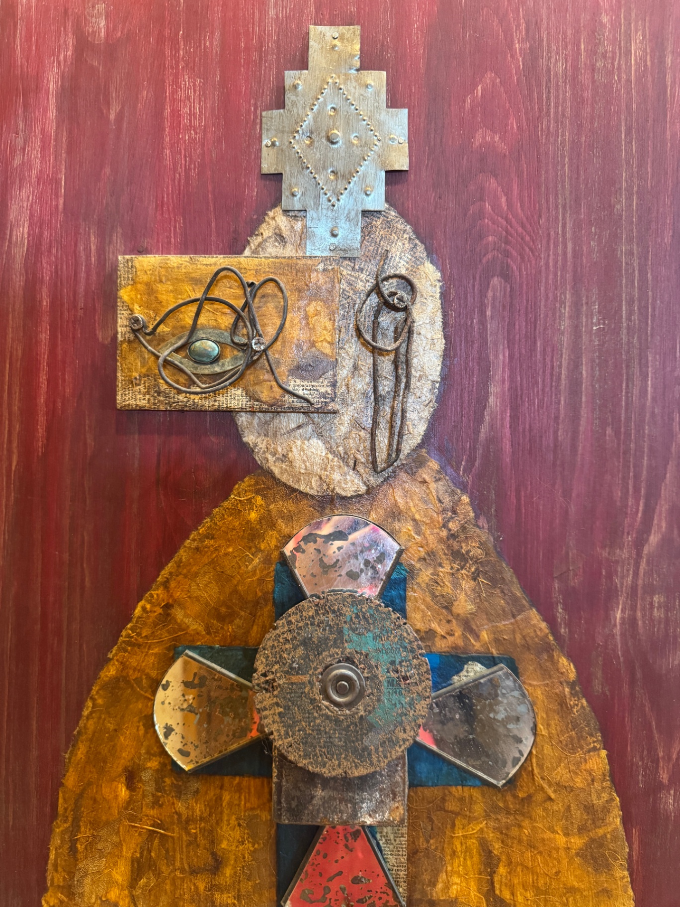 Mixed-media spirit figure artwork on a red wood background
