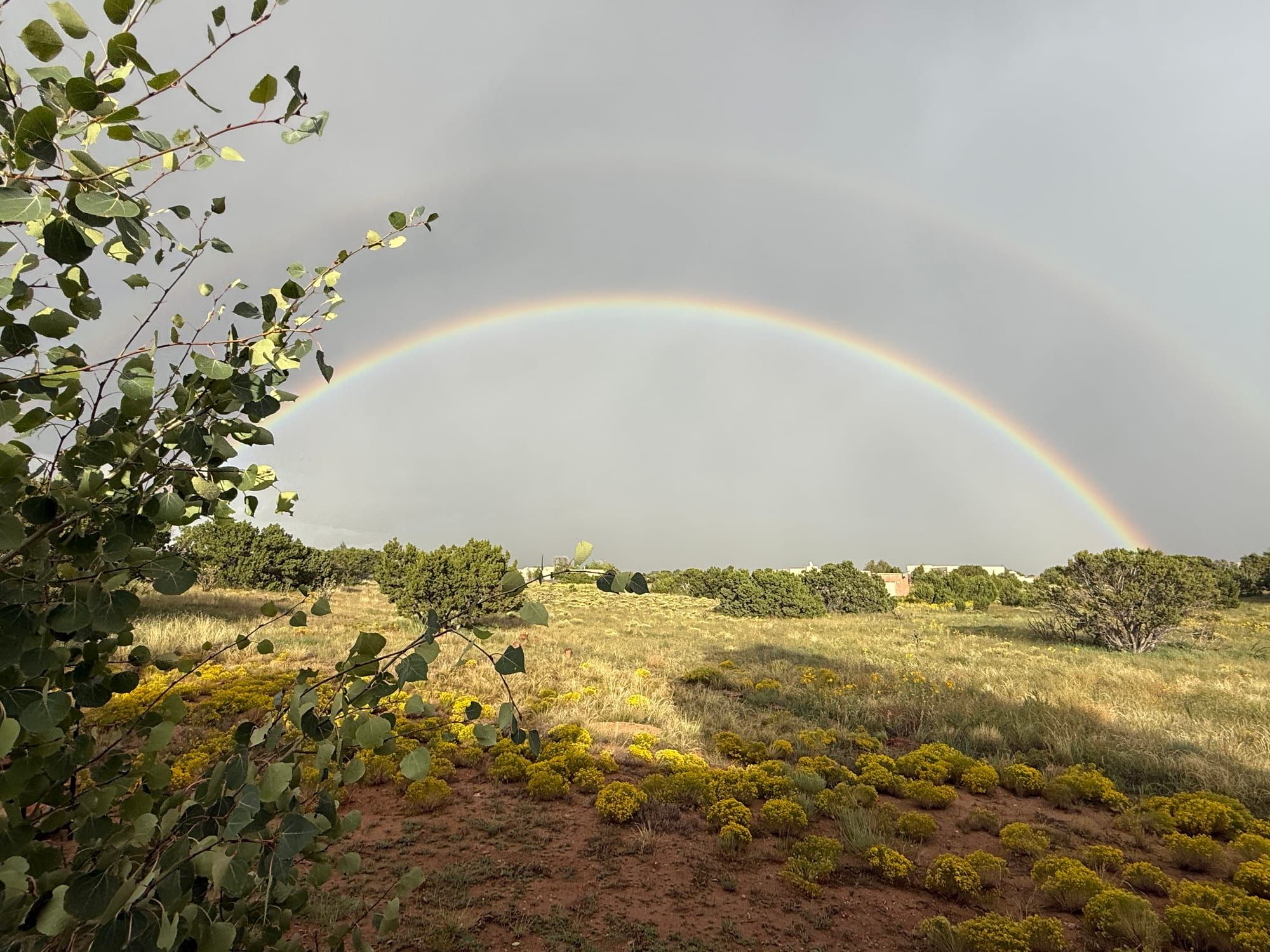 A full rainbow arcing over the high-desert landscape near Santa Fe — Shamanic Trekker — Shadow Work Guide